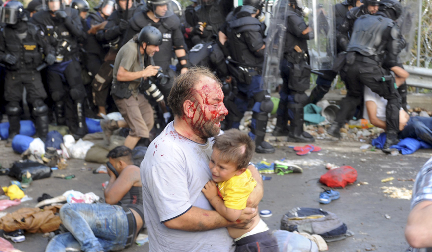 An injured migrant carries a child during clashes with Hungarian riot police at the border crossing with Serbia in Roszke, Hungary, on Wednesday (Reuters photo)